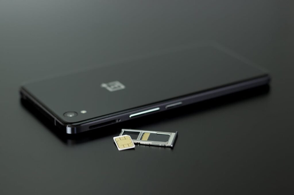 Egy lefelé fordított okostelefon fekszik az asztalon, mellette kivéve a SIM-kártya. A kép a tudatos digitális detox és a képernyőmentes időszakok fontosságát jelképezi.