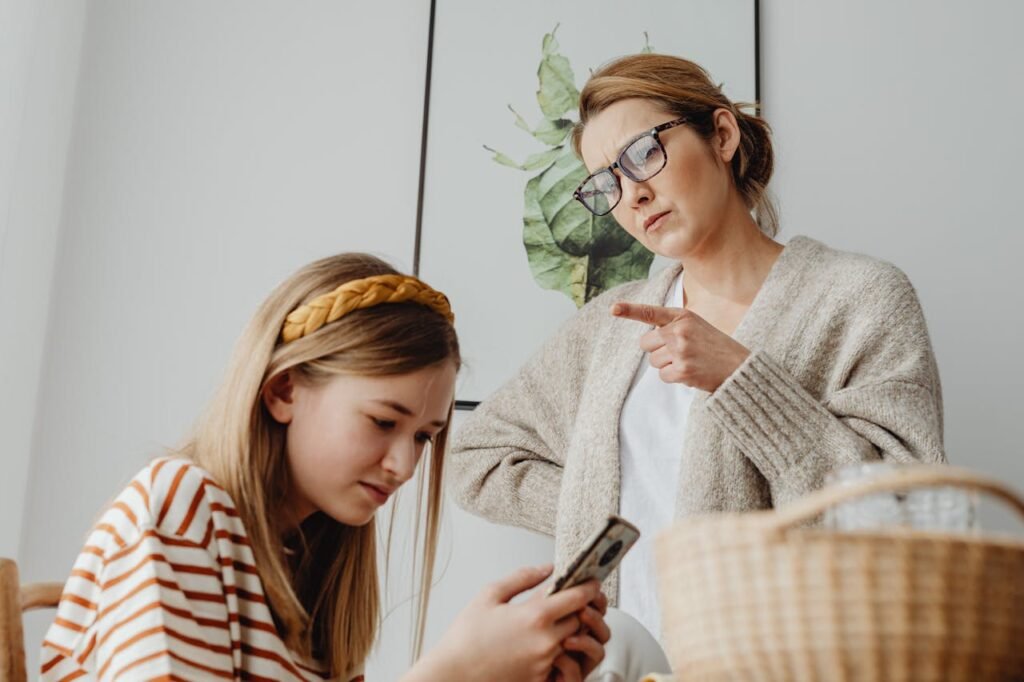 Egy anya kérdőre vonja kamasz lányát, aki folyamatosan a telefonját nyomkodja, és nem néz rá. A kép a szülő-gyermek közötti digitális konfliktusokat és a tudatos médiahasználat szükségességét ábrázolja.